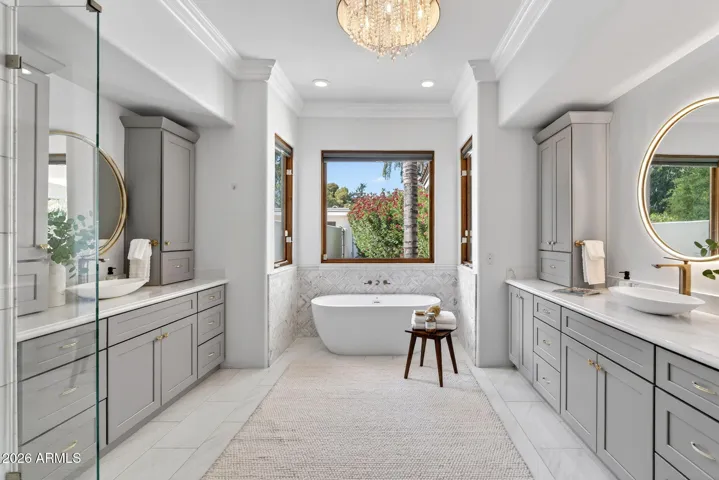 The luxurious primary bath features dual vanities with LED backlit mirrors, custom built ins, and a oversized shower with dual showerheads.