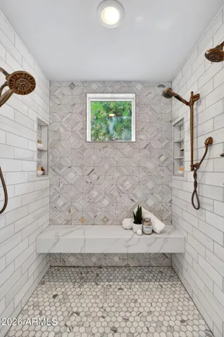 The spacious shower features multiple showerheads and bench seating.