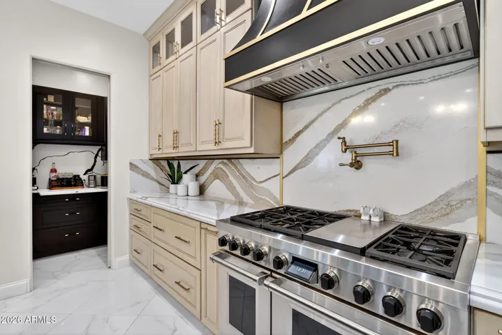 An 8 burner gas range and custom metal hood make this a cooking destination.