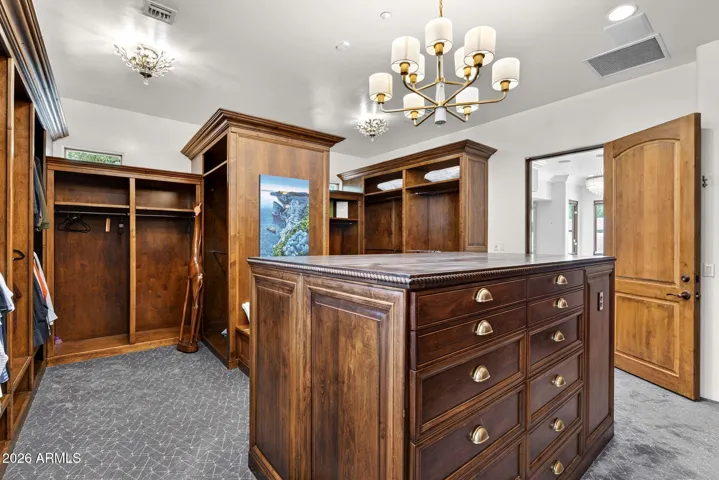 Rich custom cabinetry makes the primary closet feel like a high end retail space.