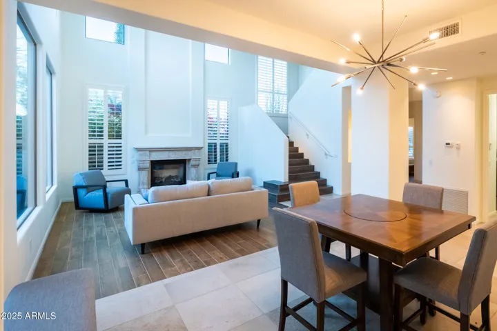 The great room, with soaring two-story ceilings and walls of glass, opens to dining area—perfect for gathering or unwinding.
