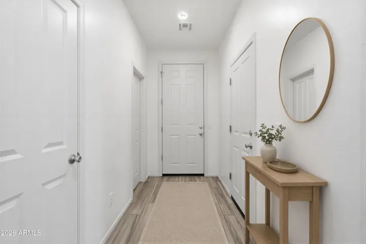 Foyer. Doors lead to a half bathroom, garage, and under-the-stairs closet. Virtually staged.