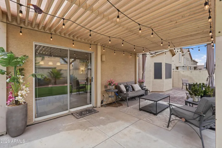 Extended covered patio with pergola, string lighting, and ample seating space—perfect for relaxing or entertaining year-round.