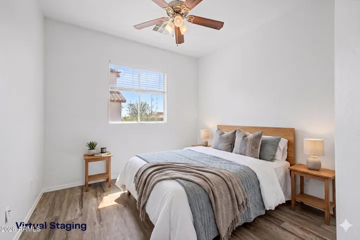 Bright bedroom features hard wood flooring, neutral paint, ceiling fan, window for natural light, and closet; minimal and move-in ready.