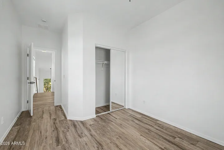 Bright bedroom with updated wood-style floors, walk-in closet and a ceiling fan. A single window provides natural light, and the simple layout offers flexible use.