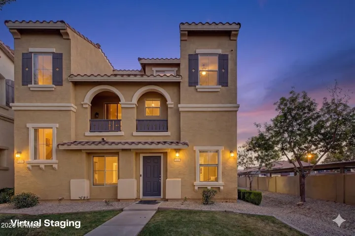 Front exterior of townhouse featuring stucco finish, tile roof, arched architectural details, private fenced yard, and covered patio.