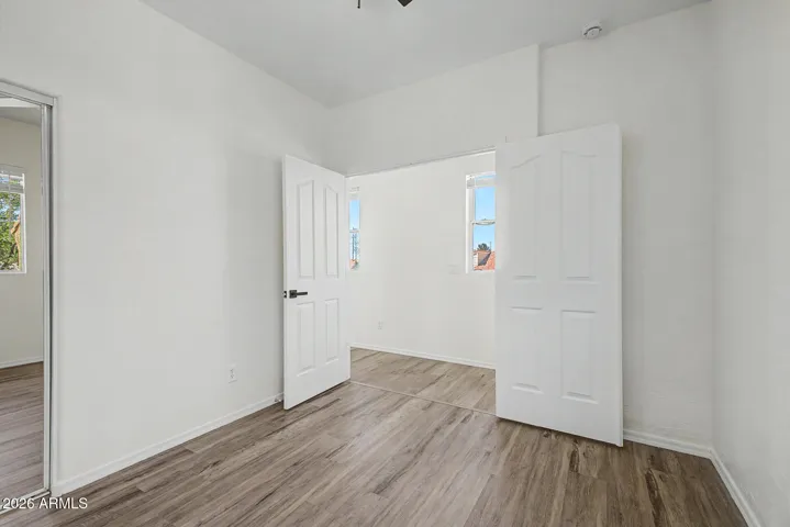 Bright bedroom features hard wood flooring, neutral paint, ceiling fan, window for natural light, and closet; minimal and move-in ready.