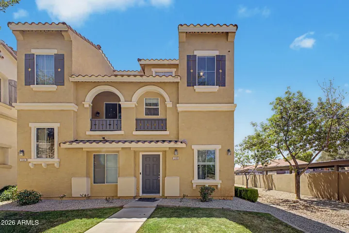 Front exterior of townhouse featuring stucco finish, tile roof, arched architectural details, private fenced yard, and covered patio.