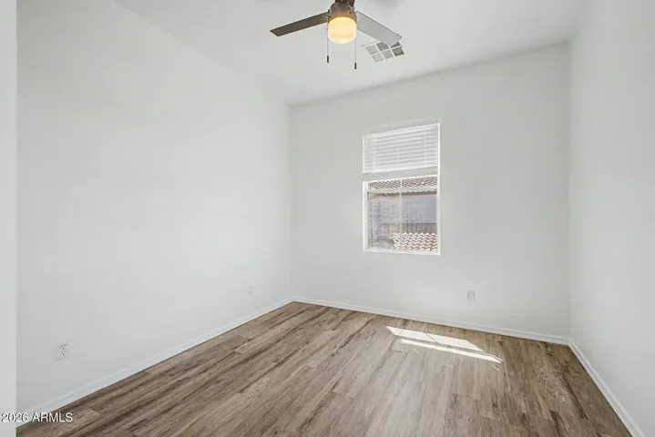 Bright bedroom with updated wood-style floors, walk-in closet and a ceiling fan. A single window provides natural light, and the simple layout offers flexible use.
