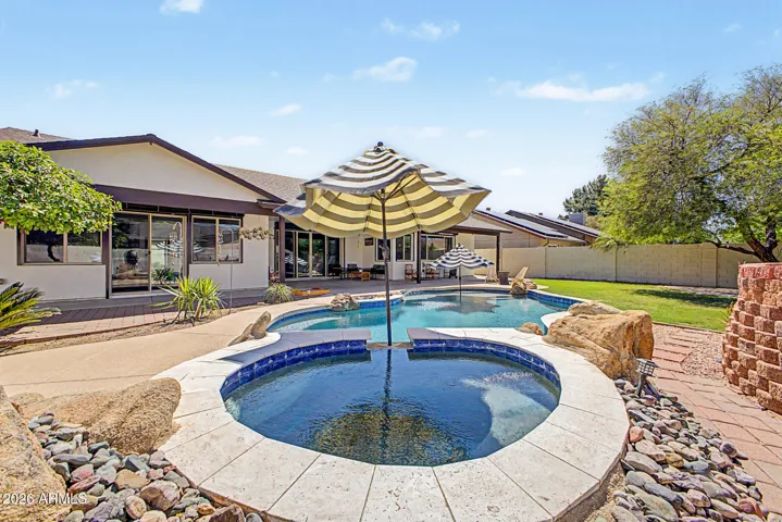 Spa & pool view to rear of home and covered patio with grass play area