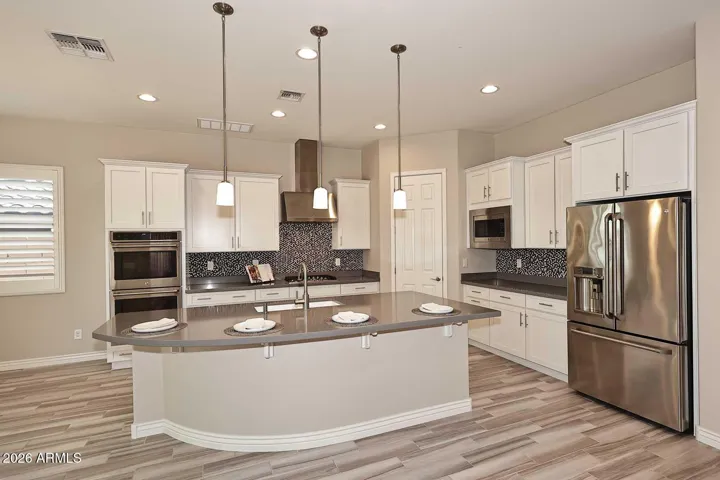 The kitchen is well-appointed with quartz countertops, double ovens, gas range, and a large island with seating for four or more, along with a true eat-in area.
