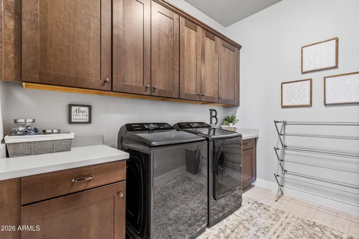 Enormous custom laundry room with high-end washer/dryer and tons of cabinets for storage.