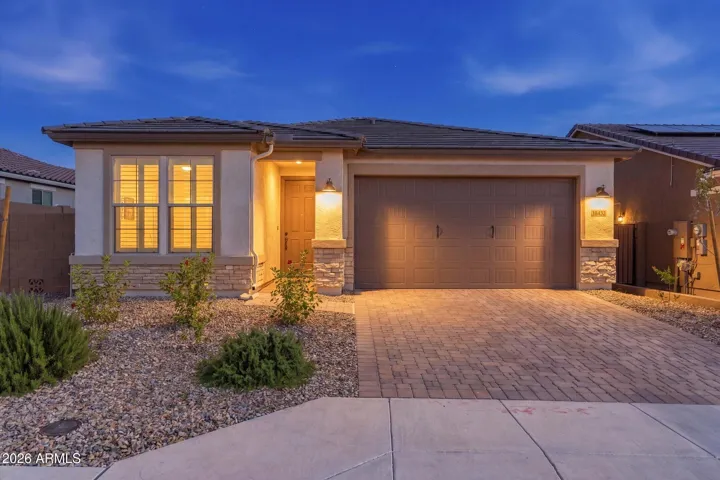 Warm twilight curb appeal with upgraded elevation, paver driveway, and inviting exterior lighting.