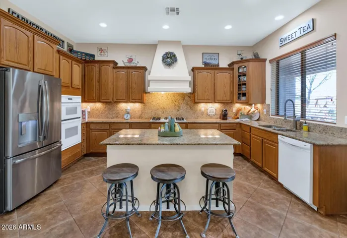 Spacious and functional kitchen featuring granite countertops, gas range, ample cabinetry, and a large center island with breakfast bar.