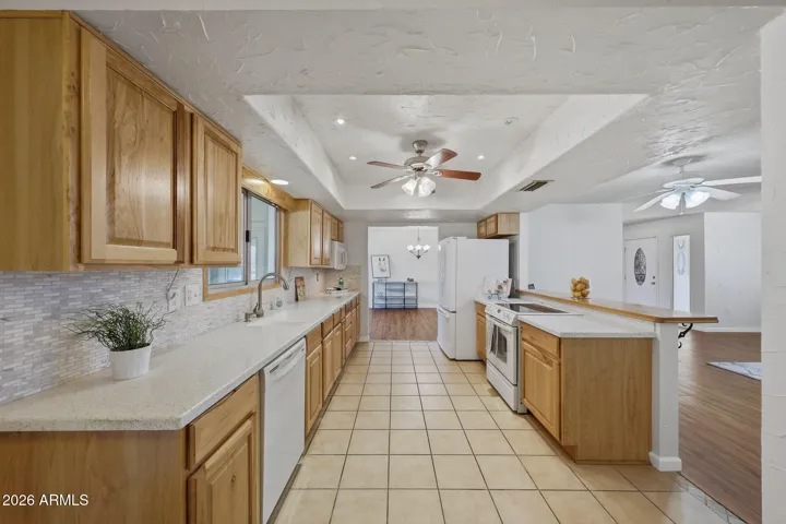 Beautiful kitchen thoughtfully updated with Corian style counter tops with glass tile backsplash, complemented by recessed lighting and opened up to the Living Room Area.