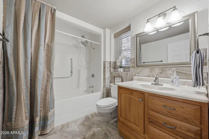 Beautifully tiled Guest Bathroom complimented with wood vanity and designer mirror.