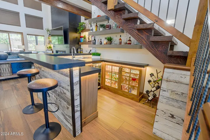Built in wet bar with floating shelfs, custom lighting, and wine fridge.