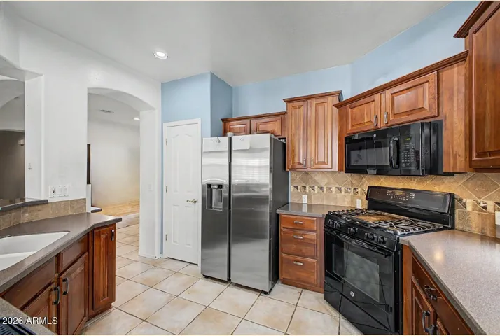 Well-appointed kitchen with gas cooktop, cherry cabinetry, Corian surfaces, pantry, and upgraded tile flooring.