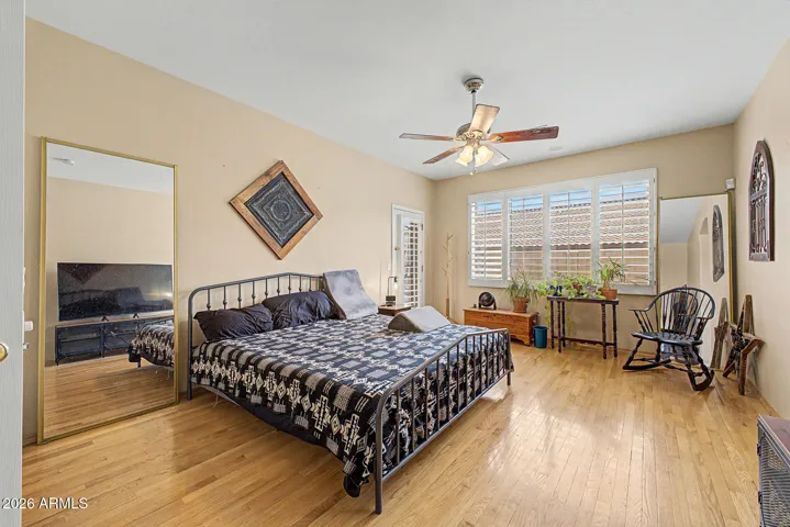 Den and primary suite showcase rich hardwood floors, plantation shutters, and ceiling fans for a cohesive, upgraded feel