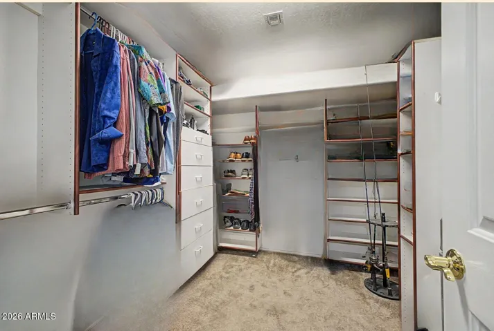 Oversized primary walk-in closet features a custom system with built-in drawers, reducing the need for additional dressers.