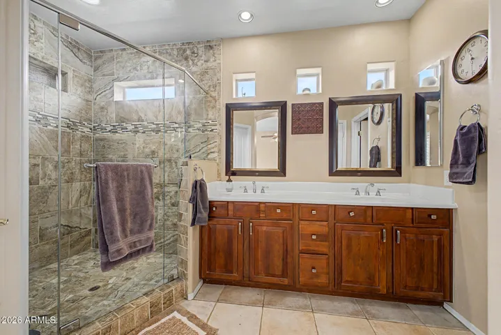 Expansive primary bath offers a dramatic oversized shower, two-sink vanity, and warm cherry cabinetry for a refined finish.