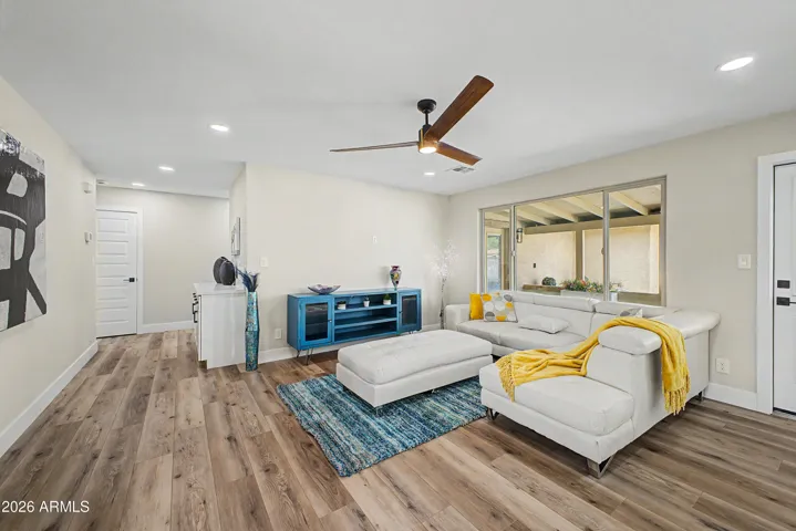 Spacious living room with modern finishes, contemporary ceiling fan, and seamless indoor-outdoor flow through oversized windows and patio access.
