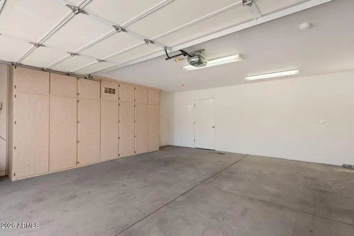 Two car garage with built-in cabinets, separate storage closet and workbench