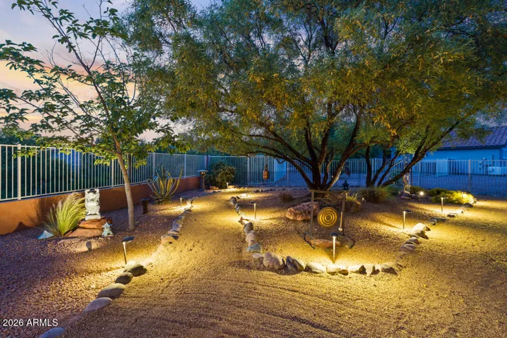 A rare, fully fenced yard opens to a beautifully designed outdoor space—where a softly lit Zen garden, mature trees, and a golf course backdrop create a serene, expansive setting.