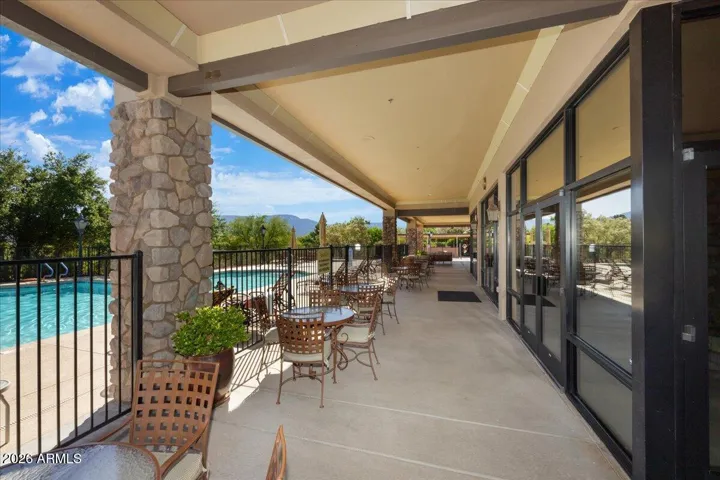 Outdoor seating under a covered patio overlooks the pool, creating an inviting space for casual conversation, quiet reading, or working on a laptop.