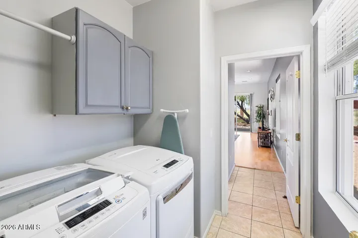 Ideally positioned between the home and attached 2-car garage, this bright laundry room features an oversized garden-facing window, built-in cabinetry for storage, and LG washer and dryer for everyday ease.