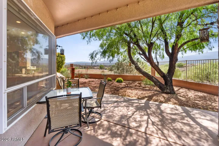 Step through sliding glass doors to an inviting outdoor dining space, where mature trees and golf course views create a natural extension of the home.