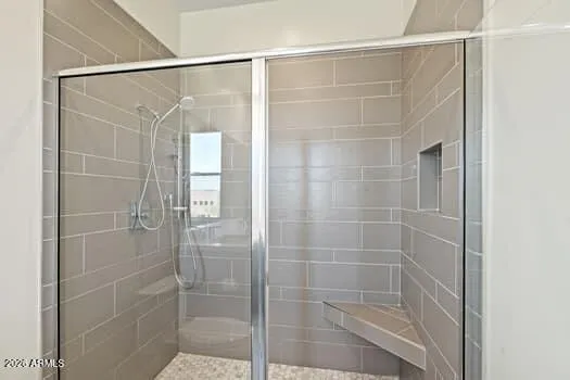 Large walk-in shower with sleek tile surround, glass enclosure, and built-in bench detail.