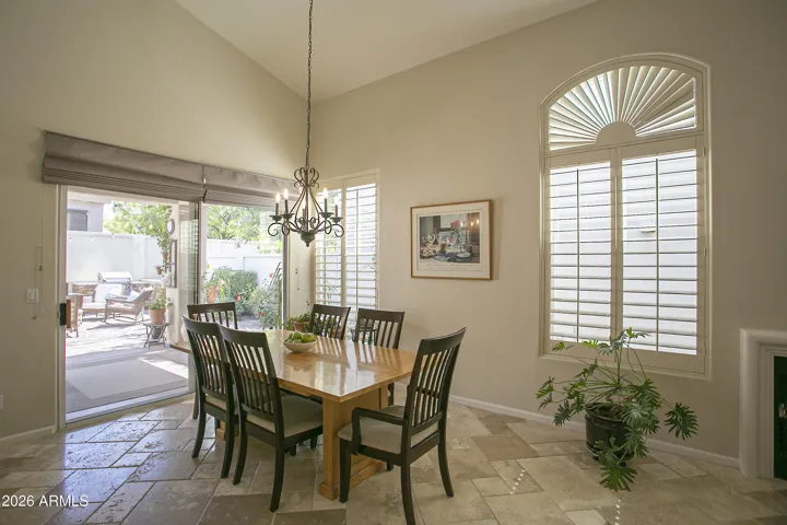 Dining area features a patio slider with custom drapes and plenty of plantation shutters.