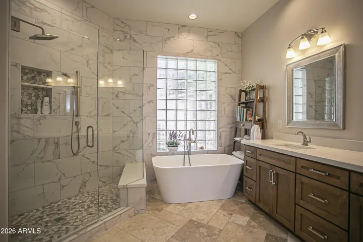 Spa-like primary bathroom with soaking tub, tiled shower and dual vanities