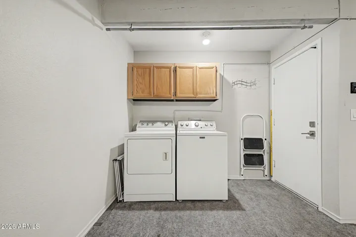 laundry area in garage with extra storage cabinets