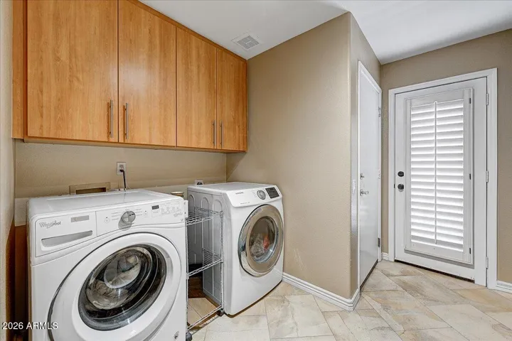 The laundry room has plenty of storage in custom cabinetry and storage closet.