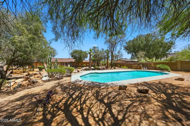 Mature landscaping in the backyard provides some shade by the pool.