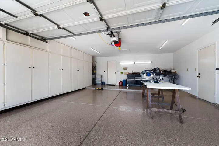 The garage with new epoxied flooring has storage cabinets.