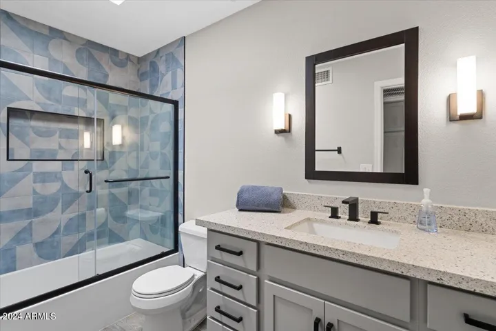 Updated guest bathroom with quartz counters and custom tile tub surround