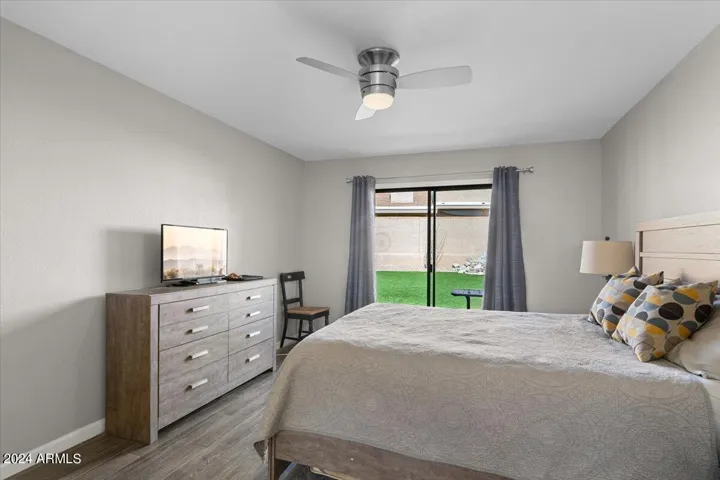 Spacious primary bedroom with sliding glass doors opening to the private backyard