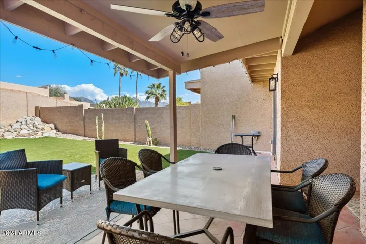 Covered patio with ceiling fan, string lights, and ample space for al fresco dining