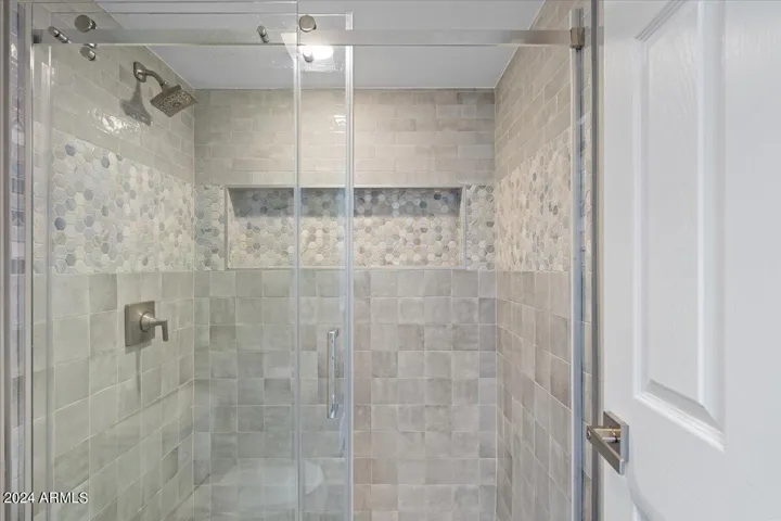 Walk-in glass shower with designer tile surround and rainfall showerhead