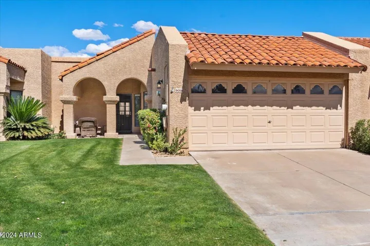 Charming single-level townhome with lush lawn, classic tile roof, and two-car garage