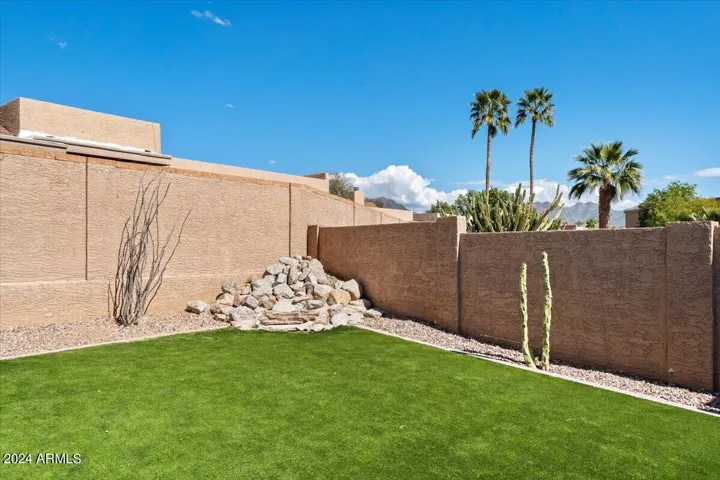 Low-maintenance lock-and-leave backyard with turf, block fencing, and desert landscaping