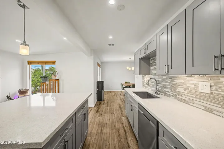This updated kitchen offers a bright, modern feel with shaker-style cabinetry, quartz countertops, stainless steel appliances, and a beautiful tile backsplash. The spacious island adds extra prep space and the perfect spot to gather, making this kitchen both stylish and functional for easy Sun City living.