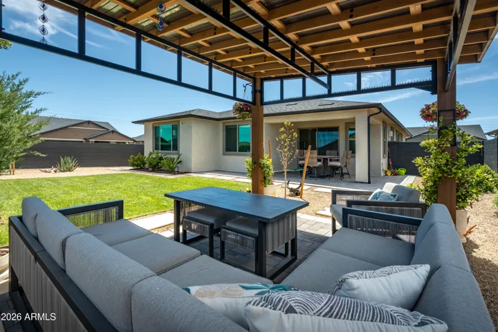 Beautiful backyard featuring a covered patio, lush lawn, and multiple seating areas, ideal for relaxing or entertaining.