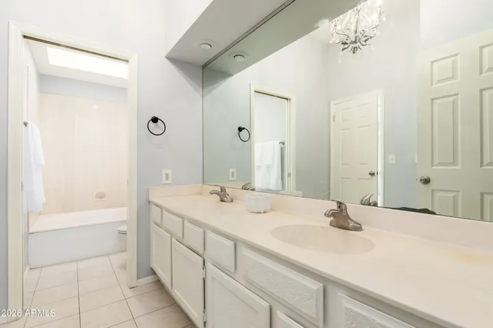 Bathroom with dual sinks and separate area/door for shower / toilet