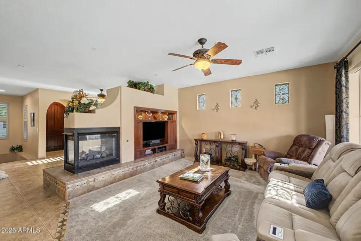 The living room’s two-way fireplace seamlessly connects to the family room, setting the stage for lively gatherings or peaceful evenings by the fire.