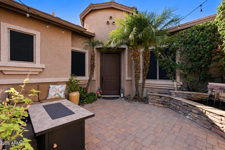 Inviting front courtyard features iron gate, pavers, & tranquil water feature