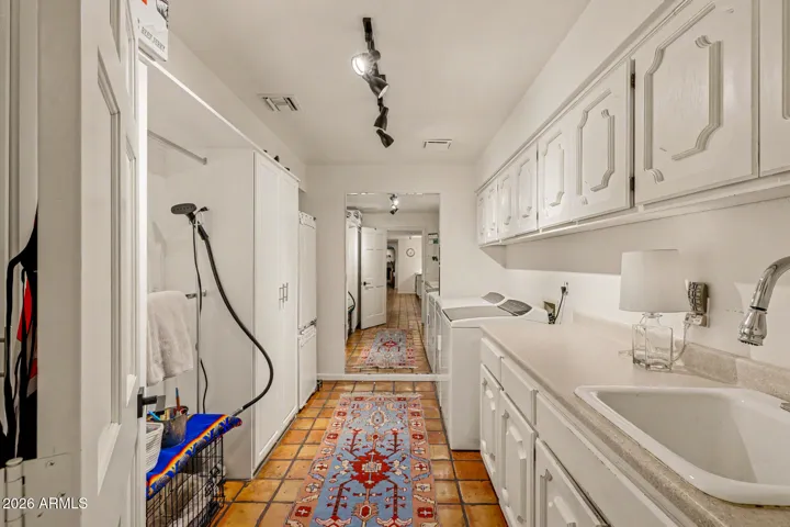 Large laundry room with pantry storage & shelves, extra cabinets & sink.
